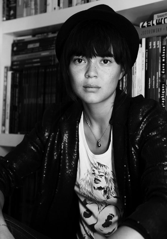 Portrait with hat in front of a bookshelf