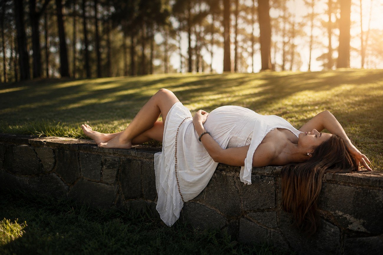 Maternity portrait, expectant mother resting on a stone wall at golden hour